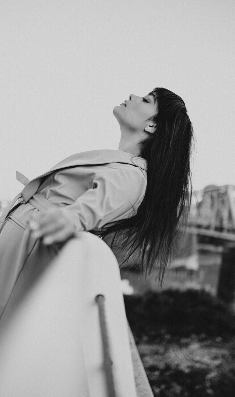 side profile of model leaning back on railing