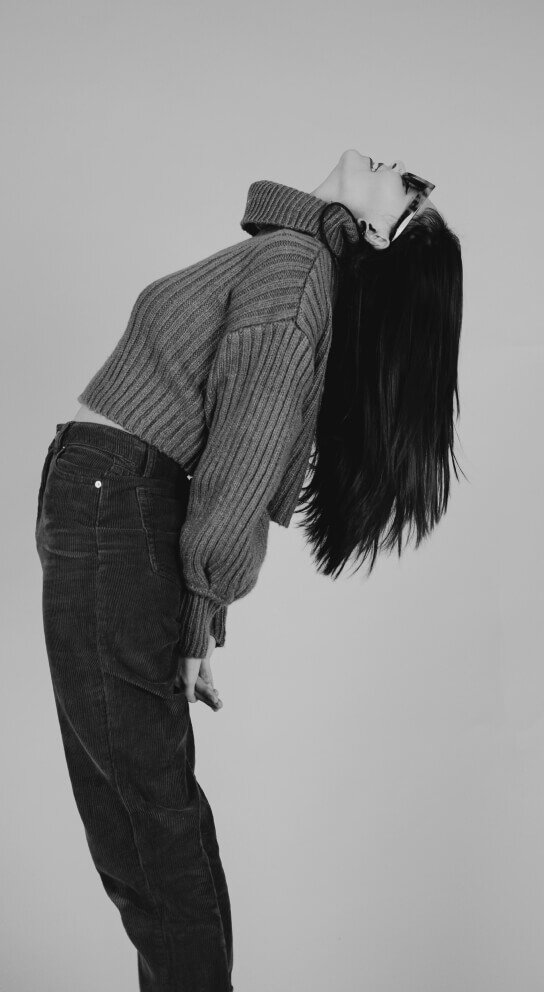 model wearing sweater and jeans and leaning back